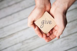 person's hands holding a block with 'give' written on it