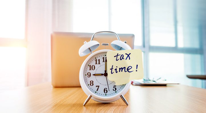 A clock with tax time sticky note on office table